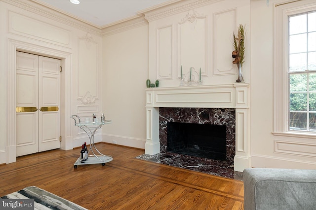 living room with hardwood / wood-style flooring, crown molding, a healthy amount of sunlight, and a premium fireplace