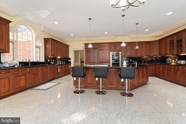 kitchen with a breakfast bar area, tasteful backsplash, crown molding, and a center island with sink