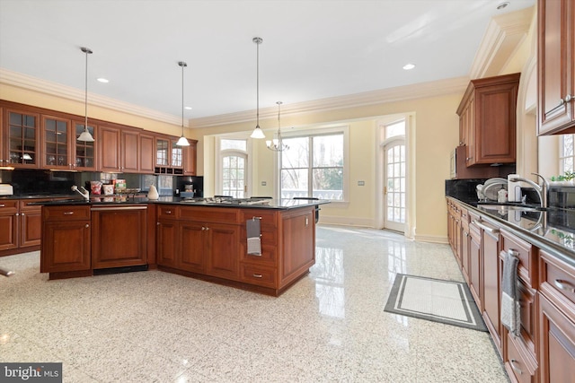 kitchen with sink, backsplash, crown molding, a chandelier, and pendant lighting