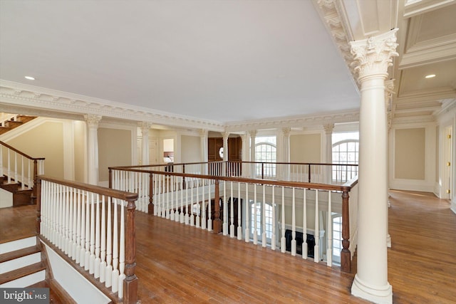 hallway featuring hardwood / wood-style flooring, ornamental molding, and ornate columns