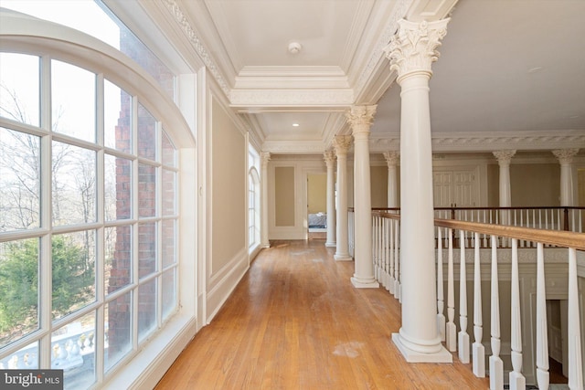 hallway with light wood-type flooring, ornamental molding, and decorative columns