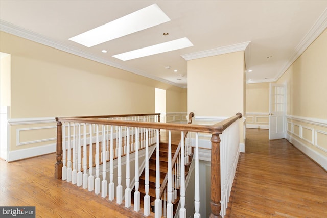 hall featuring hardwood / wood-style flooring, ornamental molding, and a skylight