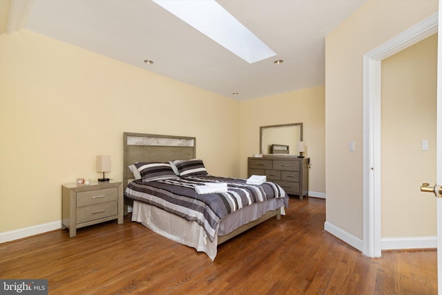 bedroom featuring a skylight and dark hardwood / wood-style flooring