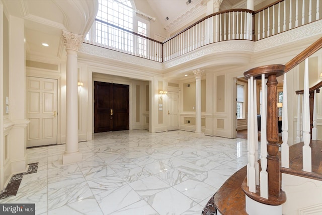 entrance foyer featuring a high ceiling, ornate columns, and ornamental molding