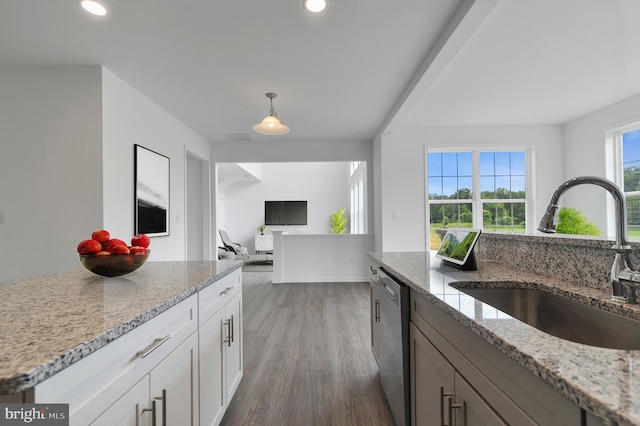 kitchen featuring dark wood-type flooring, white cabinets, sink, stainless steel dishwasher, and light stone counters