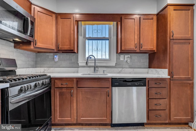 kitchen featuring appliances with stainless steel finishes, tasteful backsplash, light stone counters, light tile floors, and sink