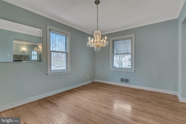 empty room with ornamental molding, a chandelier, and light wood-type flooring