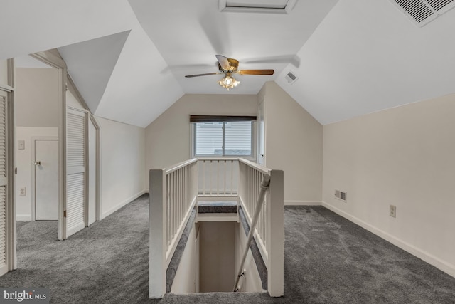 interior space featuring dark carpet, ceiling fan, and vaulted ceiling