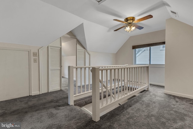 unfurnished bedroom with ceiling fan, dark carpet, and vaulted ceiling