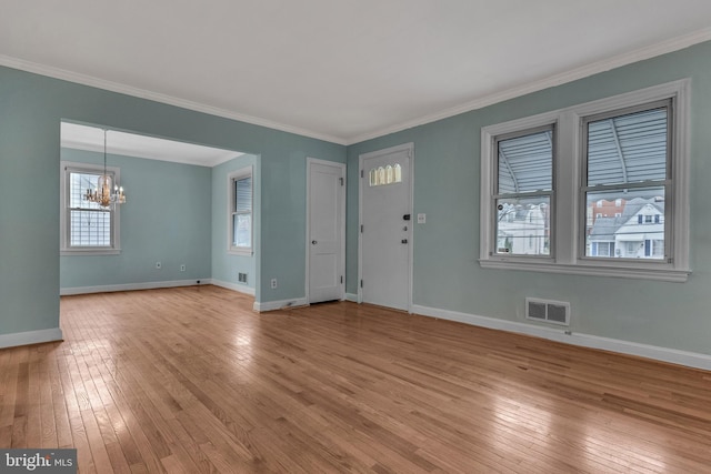 empty room featuring a chandelier, crown molding, a wealth of natural light, and light hardwood / wood-style flooring