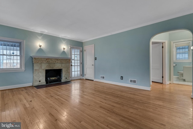 unfurnished living room with a fireplace, light wood-type flooring, and a healthy amount of sunlight