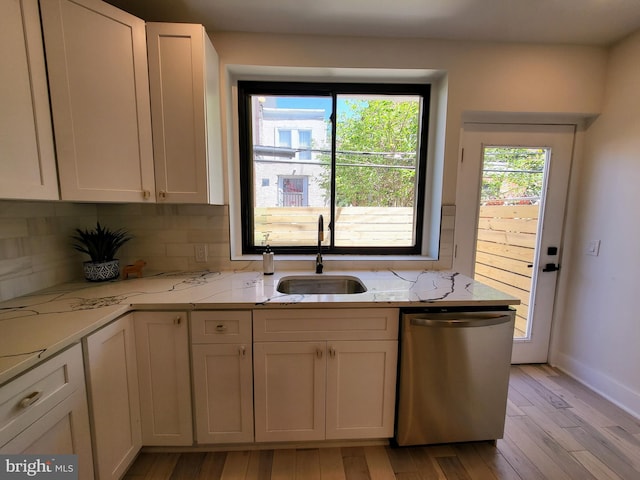 kitchen with sink, light stone counters, stainless steel dishwasher, white cabinetry, and light wood-type flooring