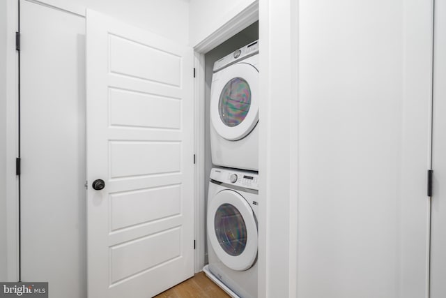 laundry area featuring stacked washing maching and dryer and light hardwood / wood-style floors