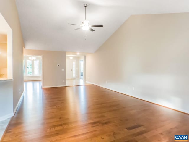 spare room featuring lofted ceiling, ceiling fan with notable chandelier, and light hardwood / wood-style flooring