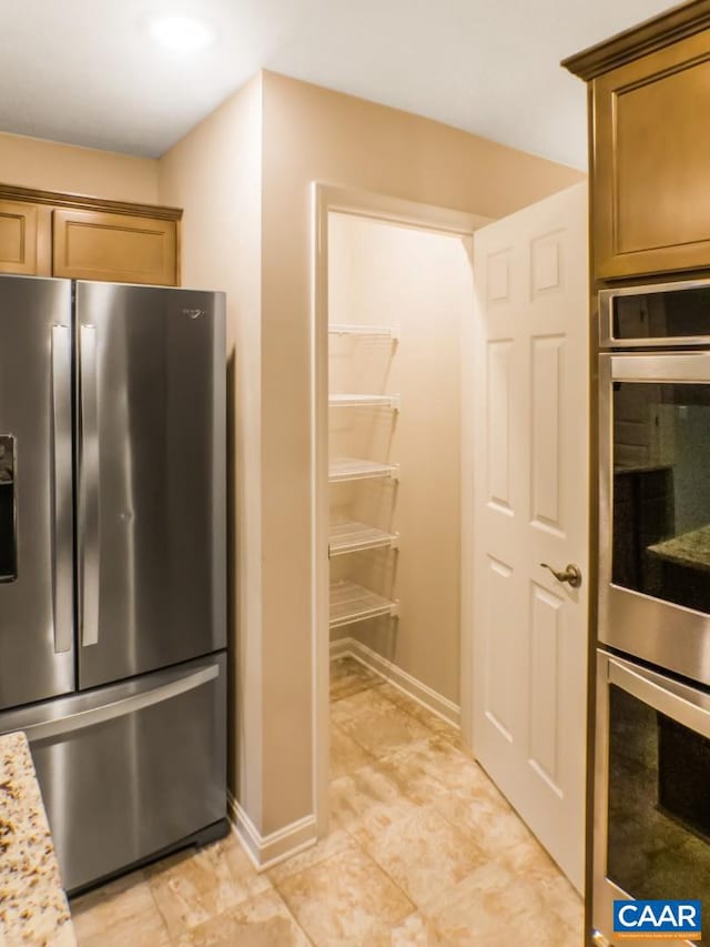 kitchen with light tile floors, appliances with stainless steel finishes, and light stone countertops