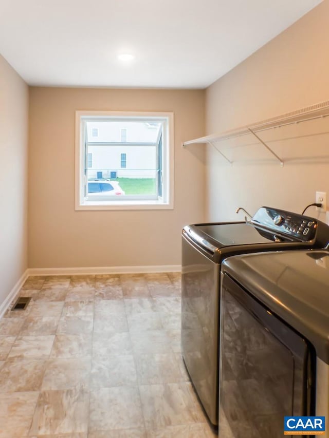 clothes washing area with washer and clothes dryer and light tile floors