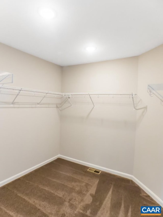 walk in closet with dark carpet