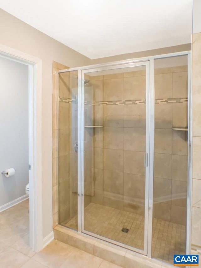 bathroom featuring an enclosed shower, toilet, and tile floors