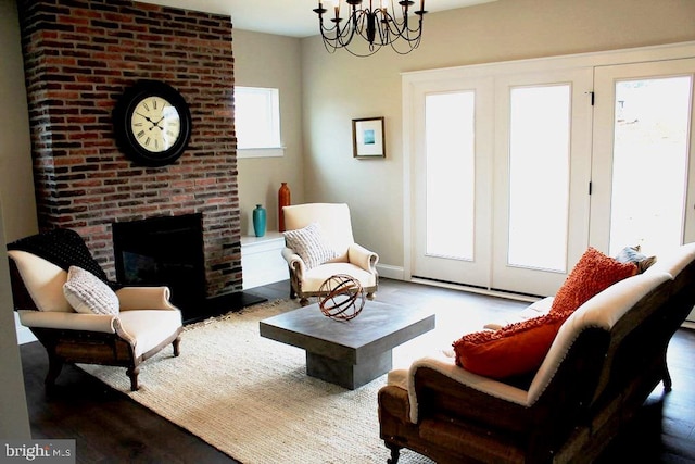 living room with dark hardwood / wood-style flooring, a brick fireplace, brick wall, and a chandelier