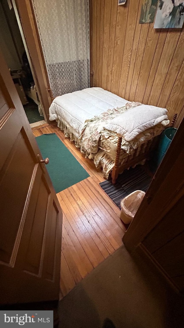 bedroom with wooden walls and hardwood / wood-style flooring