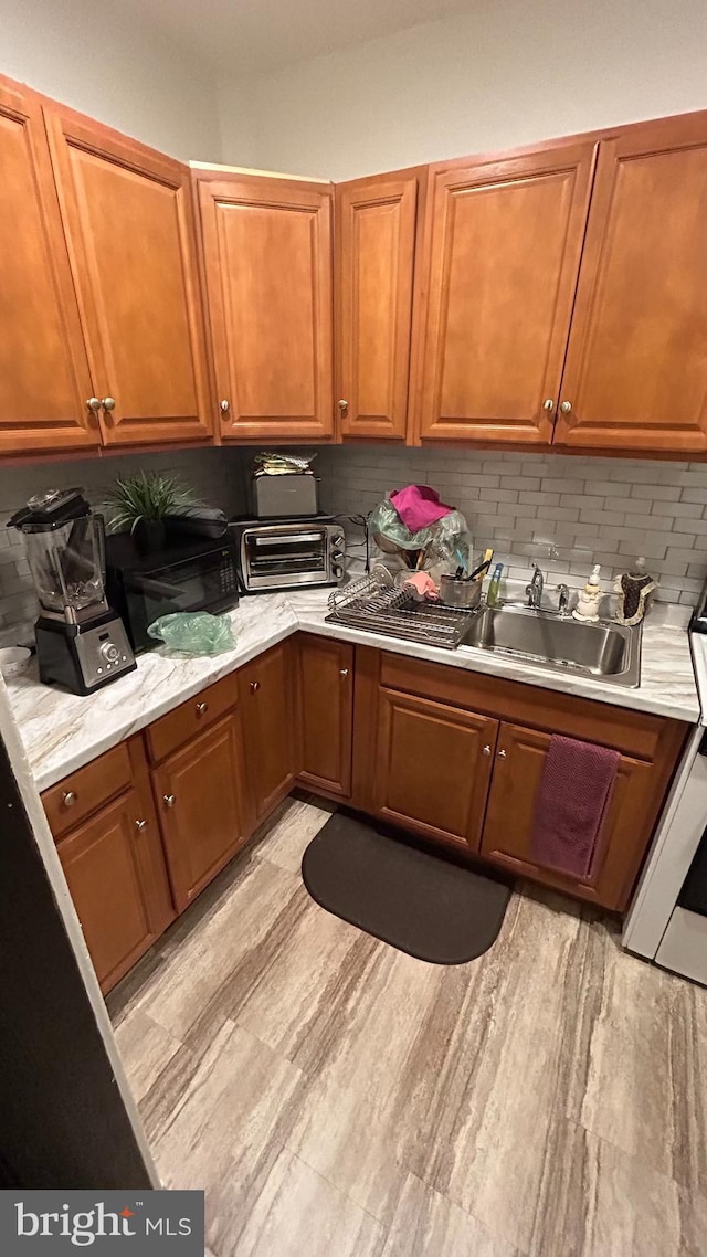 kitchen featuring sink, backsplash, range, and light hardwood / wood-style floors