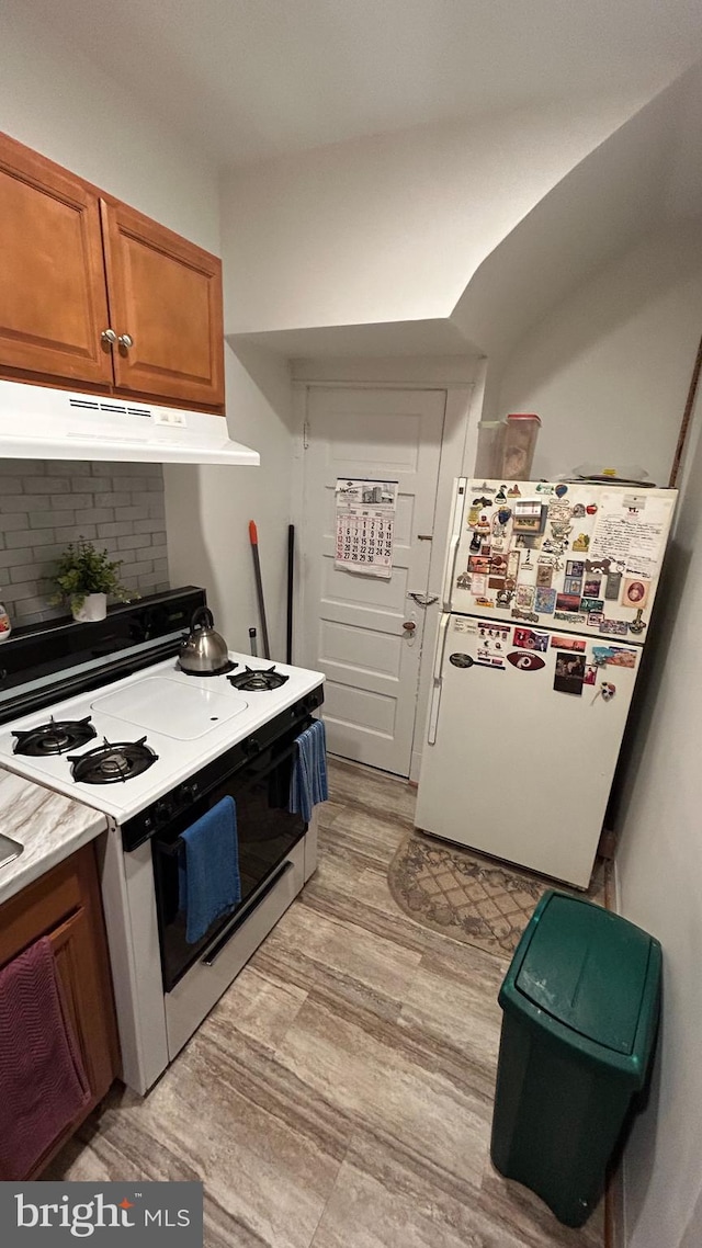 kitchen featuring tasteful backsplash, white appliances, and light hardwood / wood-style flooring