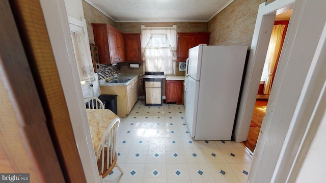 kitchen featuring white fridge, sink, backsplash, ornamental molding, and light tile flooring