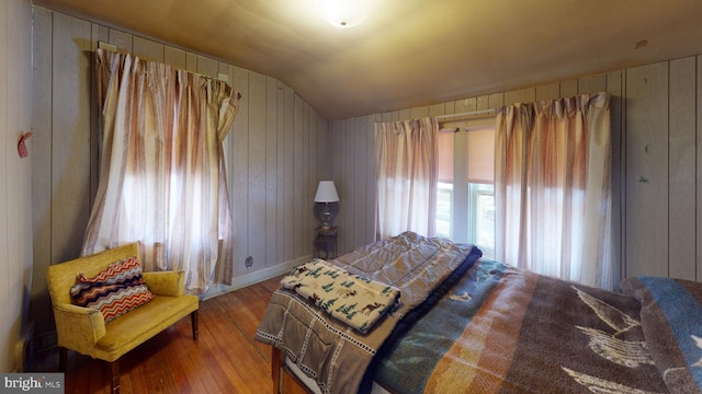 bedroom featuring wooden walls, wood-type flooring, and lofted ceiling