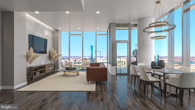 living room with a wall of windows, a healthy amount of sunlight, dark hardwood / wood-style flooring, and an inviting chandelier