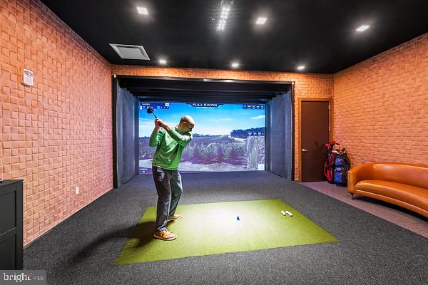 playroom featuring carpet flooring, golf simulator, and brick wall