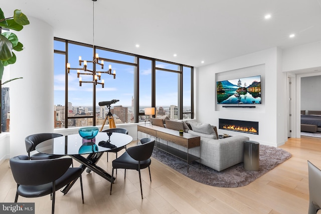 living room featuring a notable chandelier, light wood-type flooring, and floor to ceiling windows