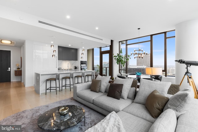 living room with light hardwood / wood-style floors, floor to ceiling windows, and a notable chandelier