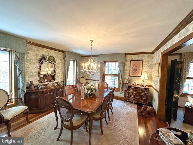 dining room featuring crown molding, light wood-type flooring, and an inviting chandelier