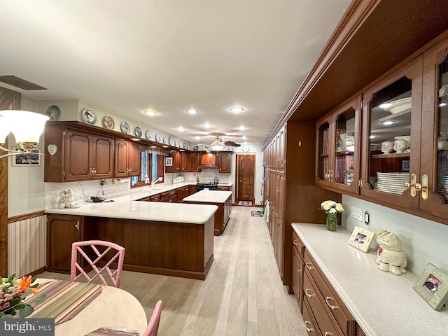 kitchen featuring kitchen peninsula, black range with electric stovetop, ceiling fan, light hardwood / wood-style floors, and sink