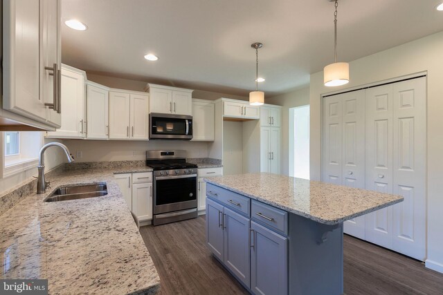 kitchen featuring a kitchen island, pendant lighting, white cabinetry, sink, and stainless steel appliances