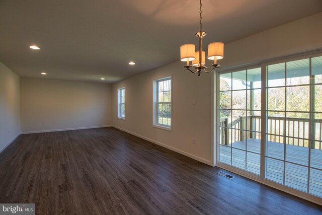 empty room with dark hardwood / wood-style flooring and a notable chandelier