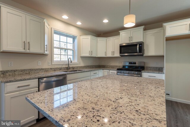 kitchen featuring sink, white cabinetry, decorative light fixtures, stainless steel appliances, and light stone countertops