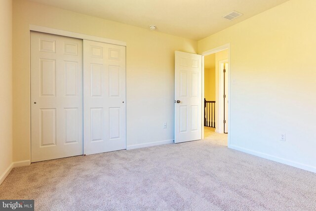 unfurnished bedroom featuring light colored carpet and a closet