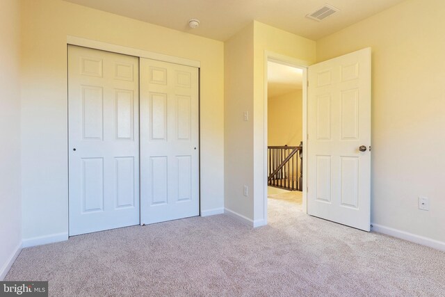 unfurnished bedroom with light carpet and a closet