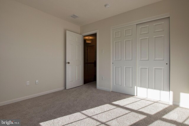 unfurnished bedroom with light colored carpet and a closet