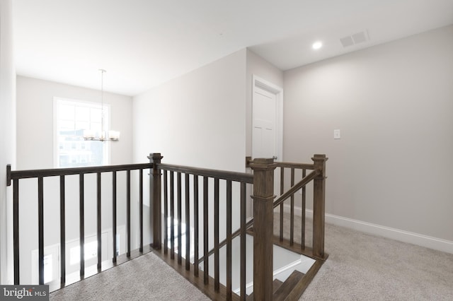 hall featuring an inviting chandelier and carpet flooring