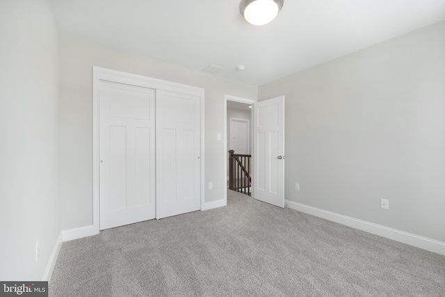 unfurnished bedroom featuring light carpet and a closet