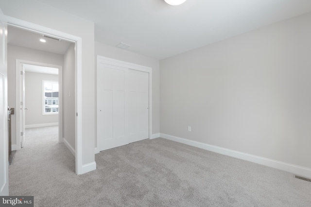 unfurnished bedroom featuring light colored carpet and a closet