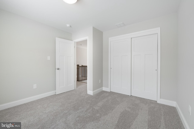 unfurnished bedroom featuring light carpet and a closet