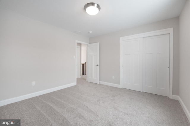 unfurnished bedroom featuring light colored carpet and a closet