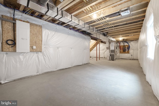 basement featuring electric panel and heating unit