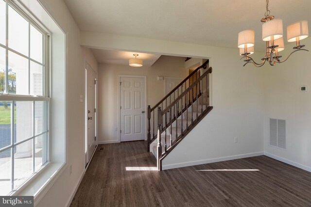 entryway with dark hardwood / wood-style floors and a notable chandelier