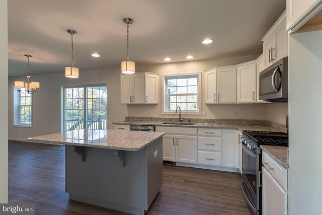 kitchen with white cabinetry, stainless steel appliances, decorative light fixtures, and sink