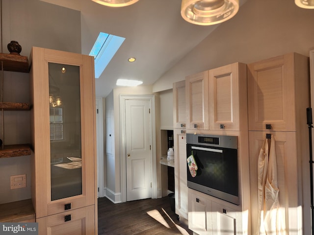 kitchen featuring light brown cabinetry, lofted ceiling with skylight, dark hardwood / wood-style flooring, and oven