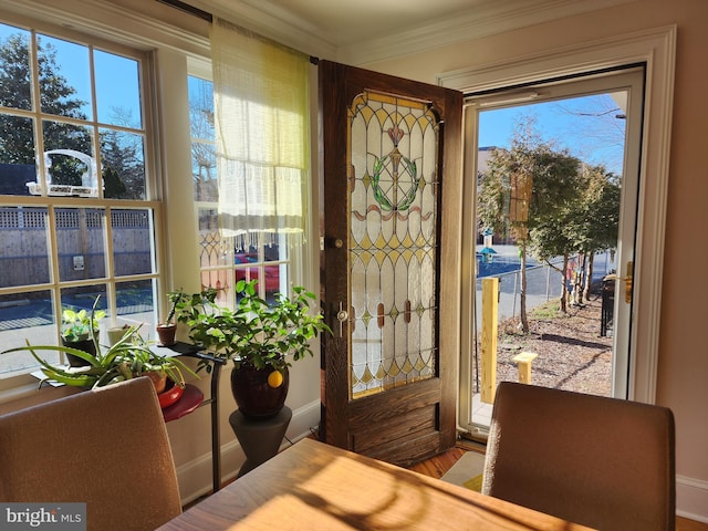 doorway with hardwood / wood-style floors, a wealth of natural light, and ornamental molding